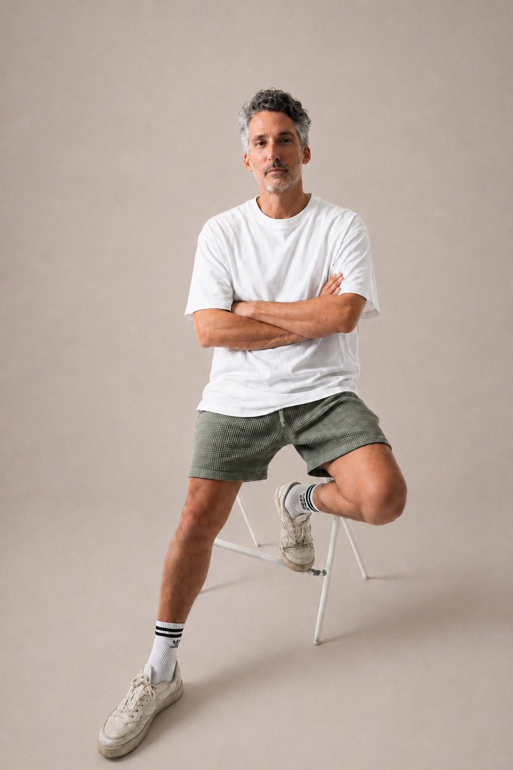 Portrait studio de Keys on the P., assis sur un tabouret, bras croises