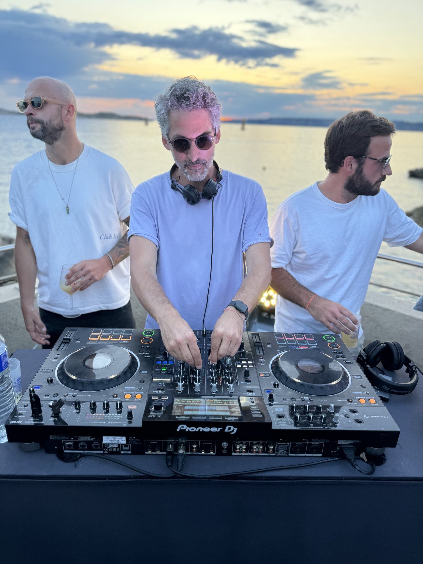 Set au coucher du soleil face a la mer, trois artistes aux platines